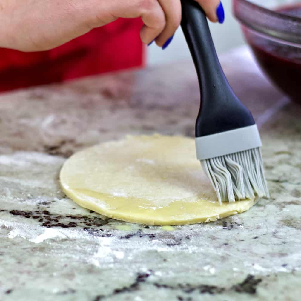 brushing dough edge with egg wash.