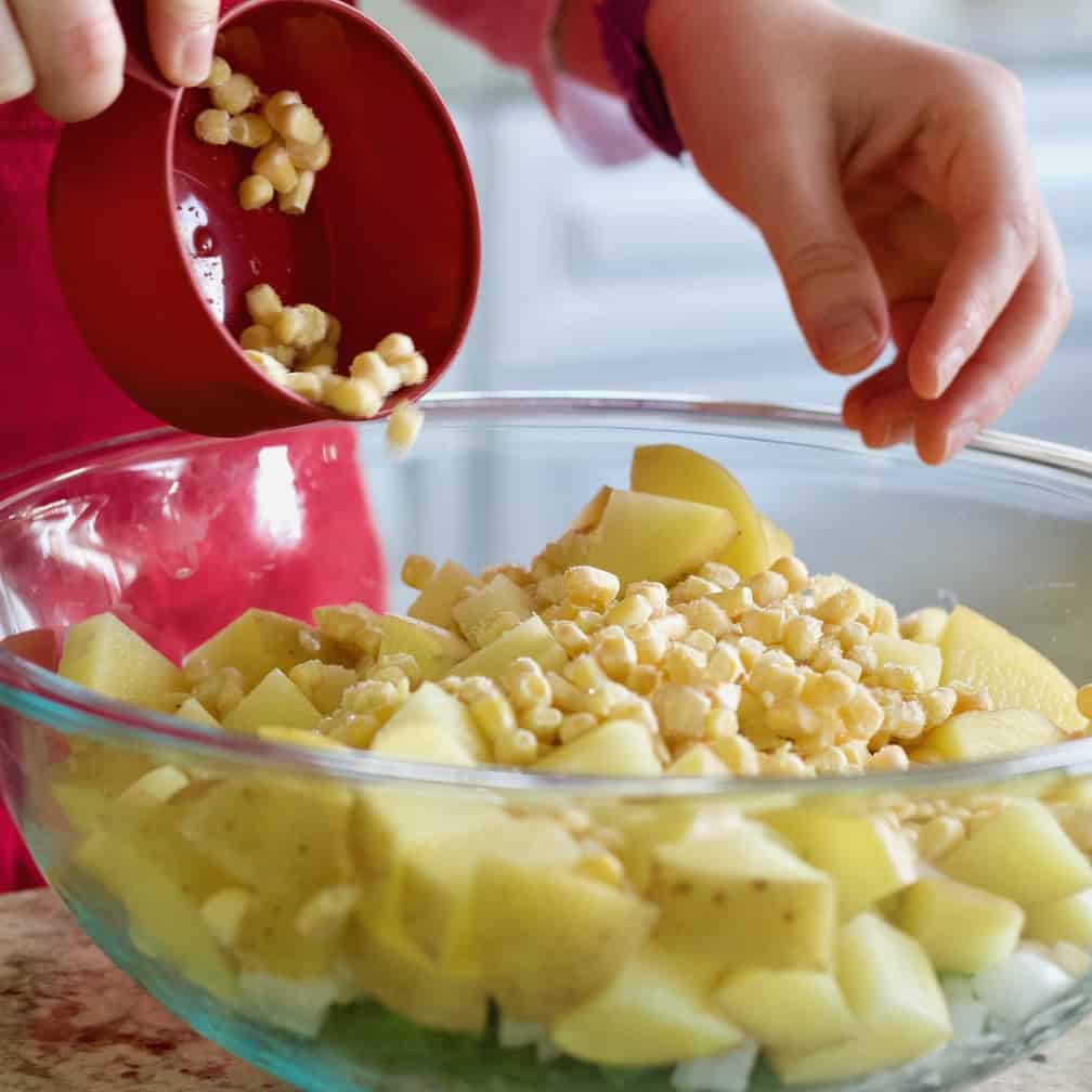 pouring frozen corn into bowl of vegetables