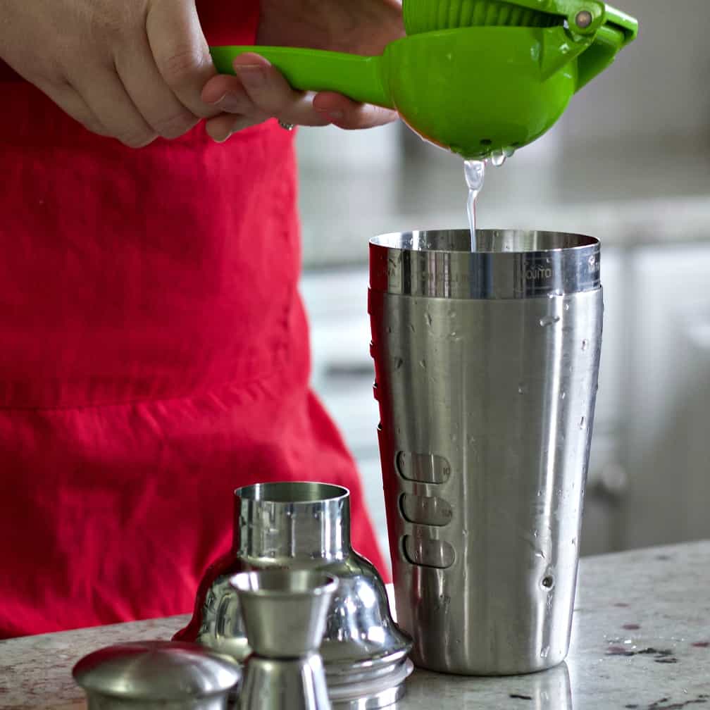 squeezing lemon juice into shaker