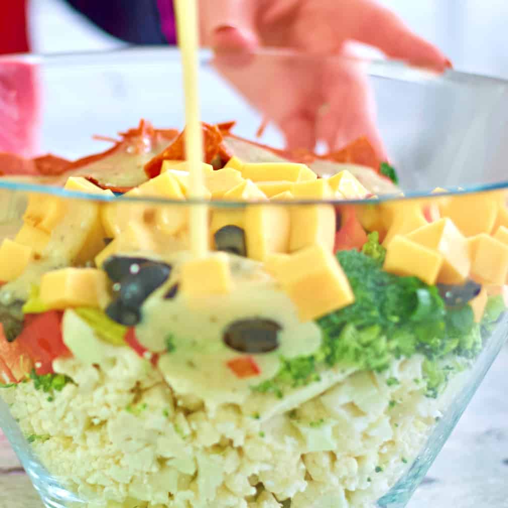 pouring Italian dressing over cauliflower salad