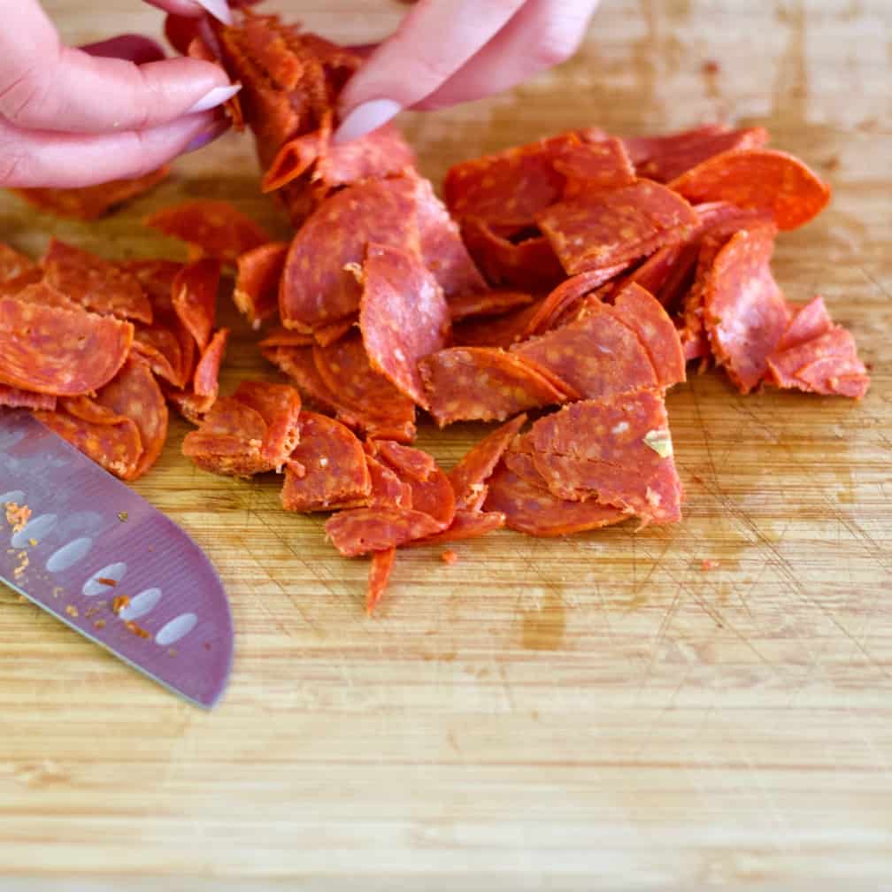 chopping sliced pepperoni -cauliflower salad