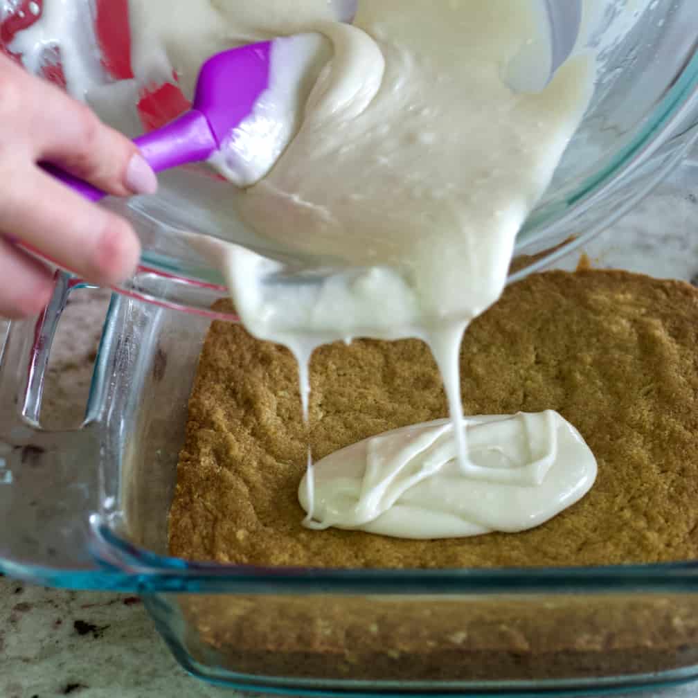 pouring frosting on lemon crust.
