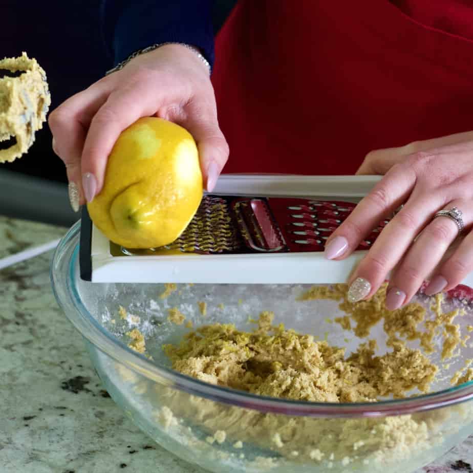 zesting a lemon into lemon cookie bar dough.