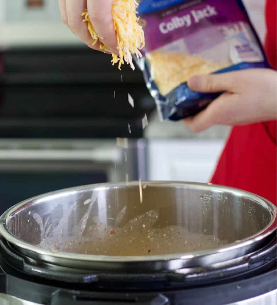 sprinkling colby cheese into chicken chili