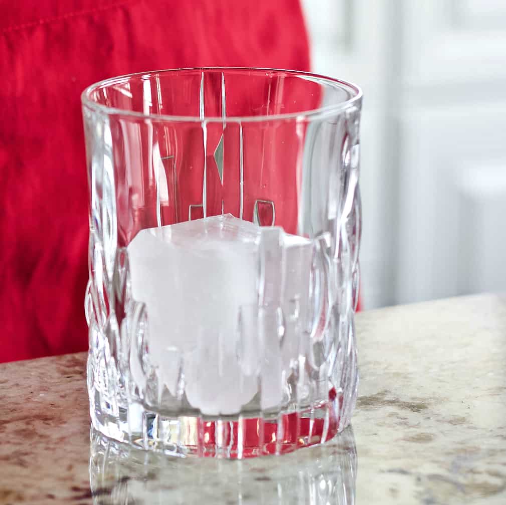 whiskey glass with large square ice cube. peach crown royal