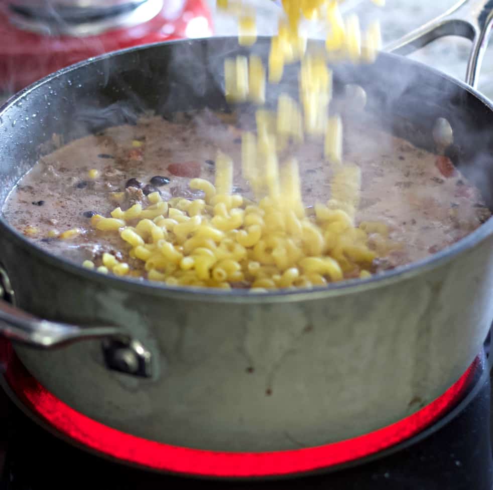 Pouring pasta into chili mac