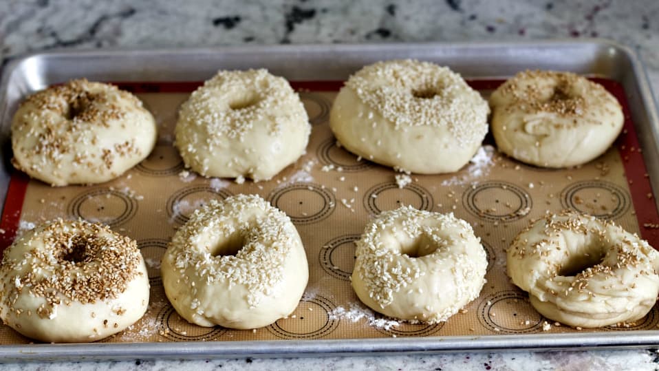 raw sourdough bagels on baking pan