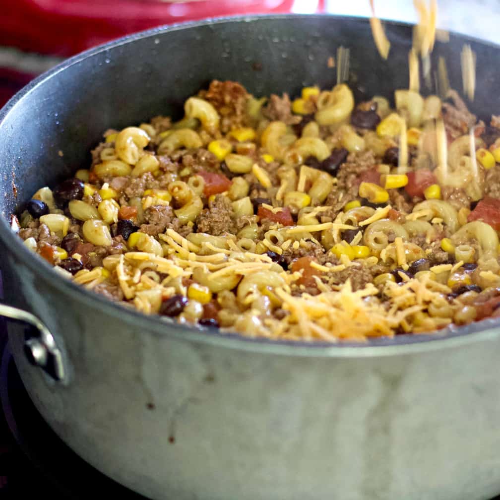 Sprinkling cheese over chili mac