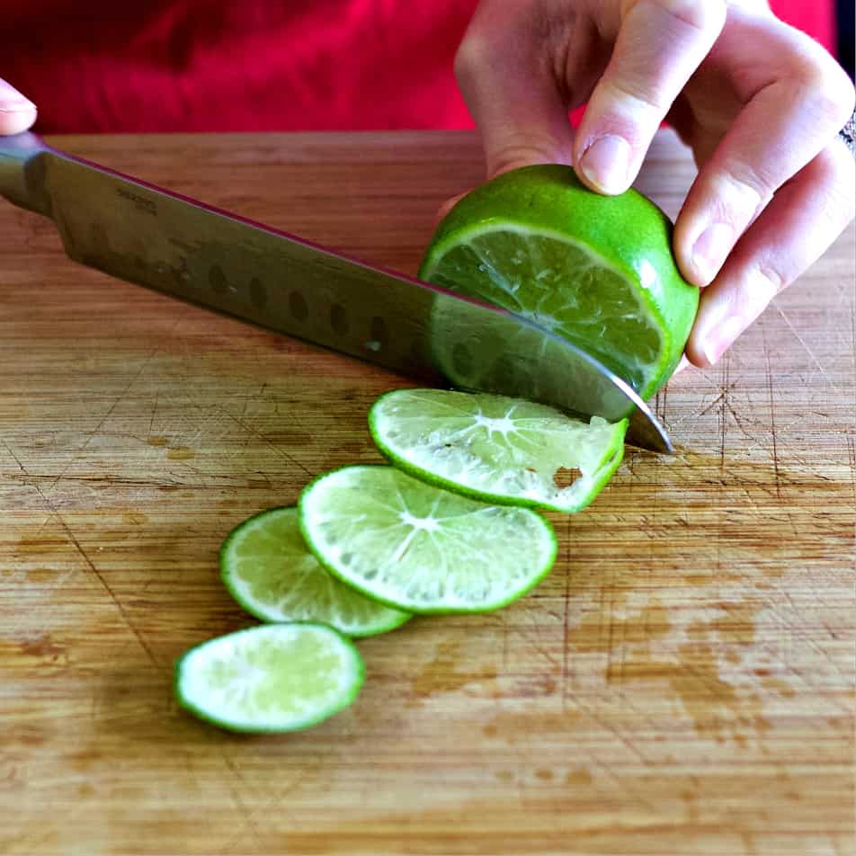 Slicing a fresh lime-Mezcal cocktail