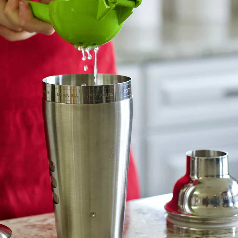 squeezing a lime into a cocktail shaker. Mezcal cocktail