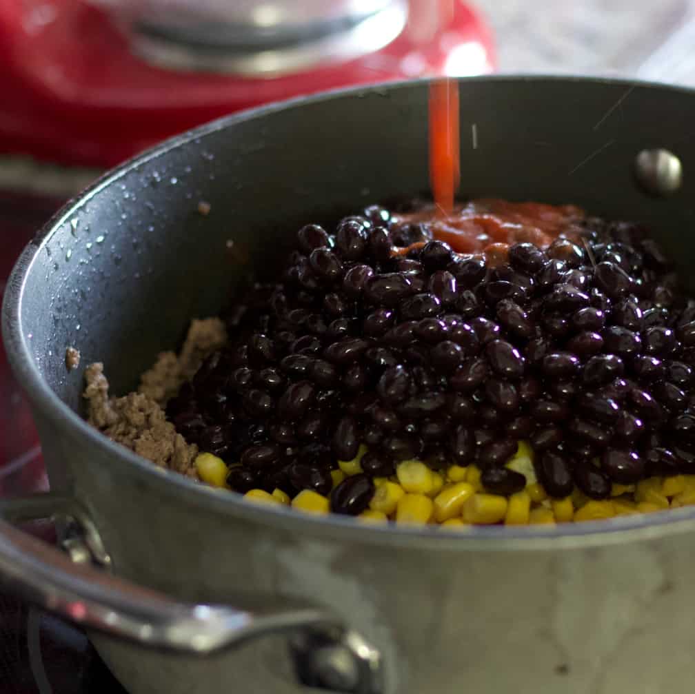 Pouring tomato sauce into hamburger dinner