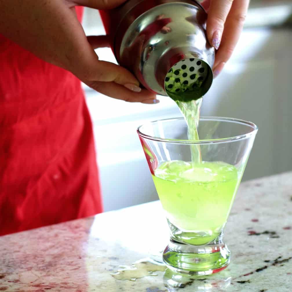 straining Midori sour into glass