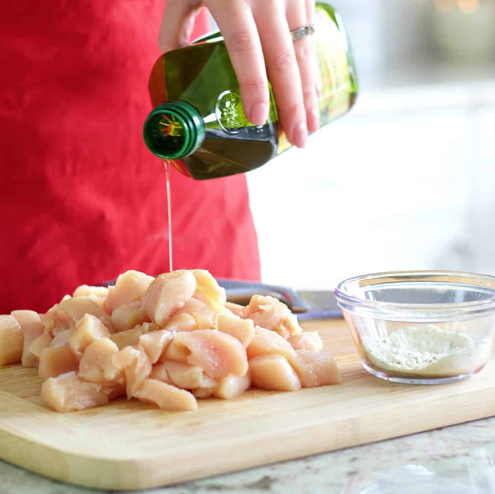 Chicken Bacon Ranch Casserole Recipe 5 pouring oil over chopped chicken on wooden board