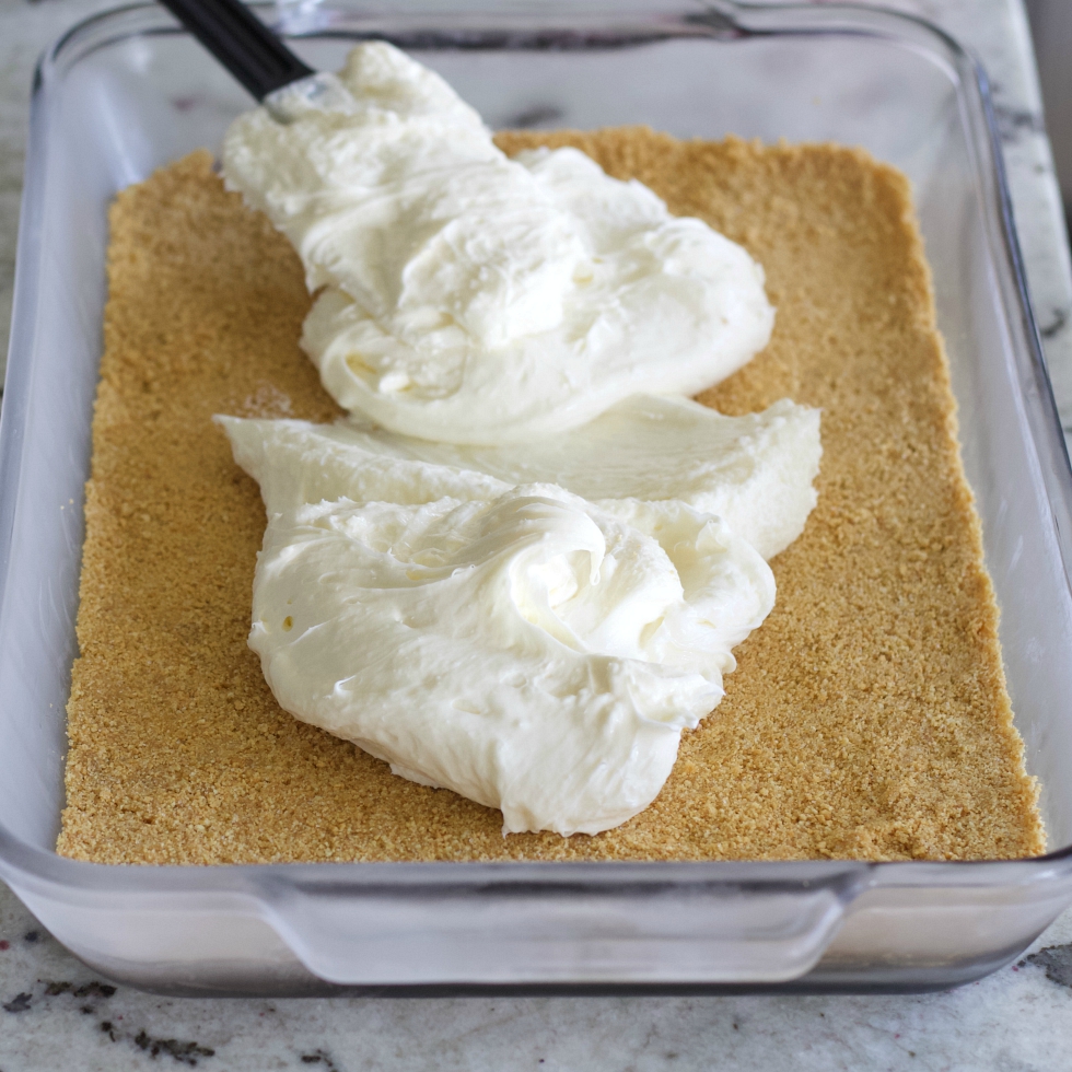 spreading cream cheese layer over chilled graham crust