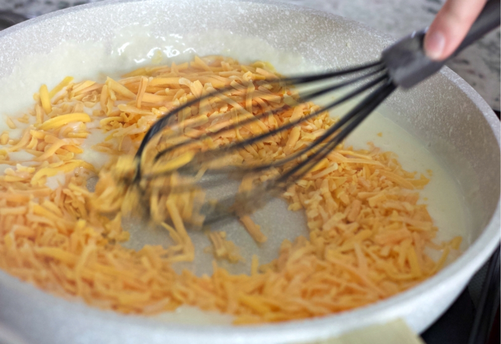 whisking in shredded cheese