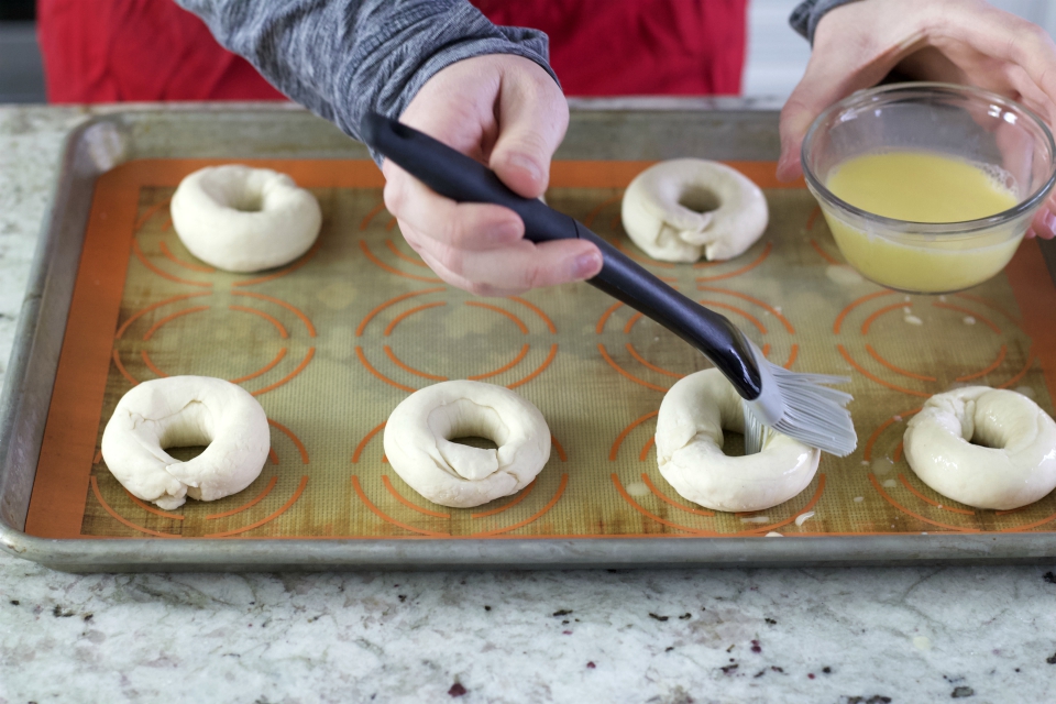 brushing egg wash on bagels
