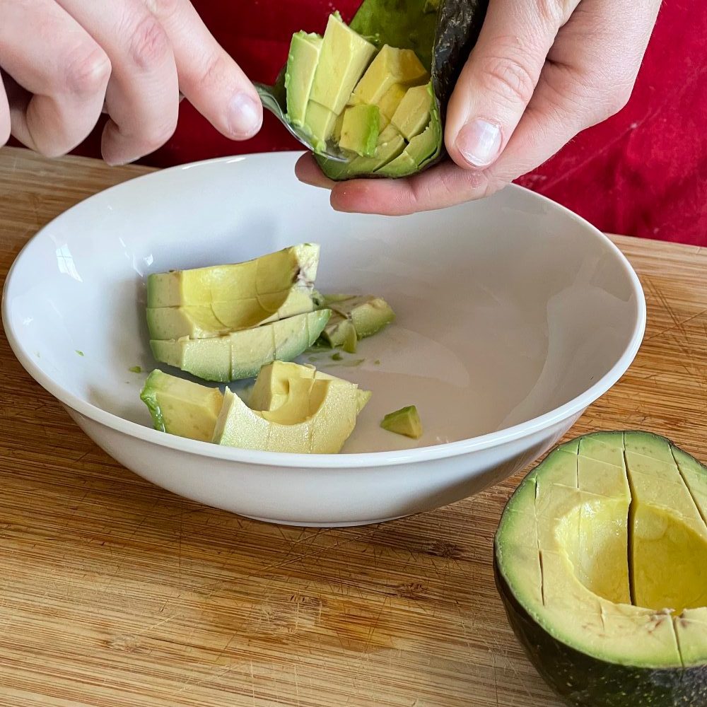scooping chopped avocado out of skin into bowl