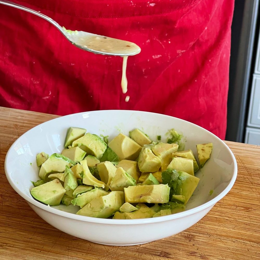 drizzling greek salad over chopped avocado