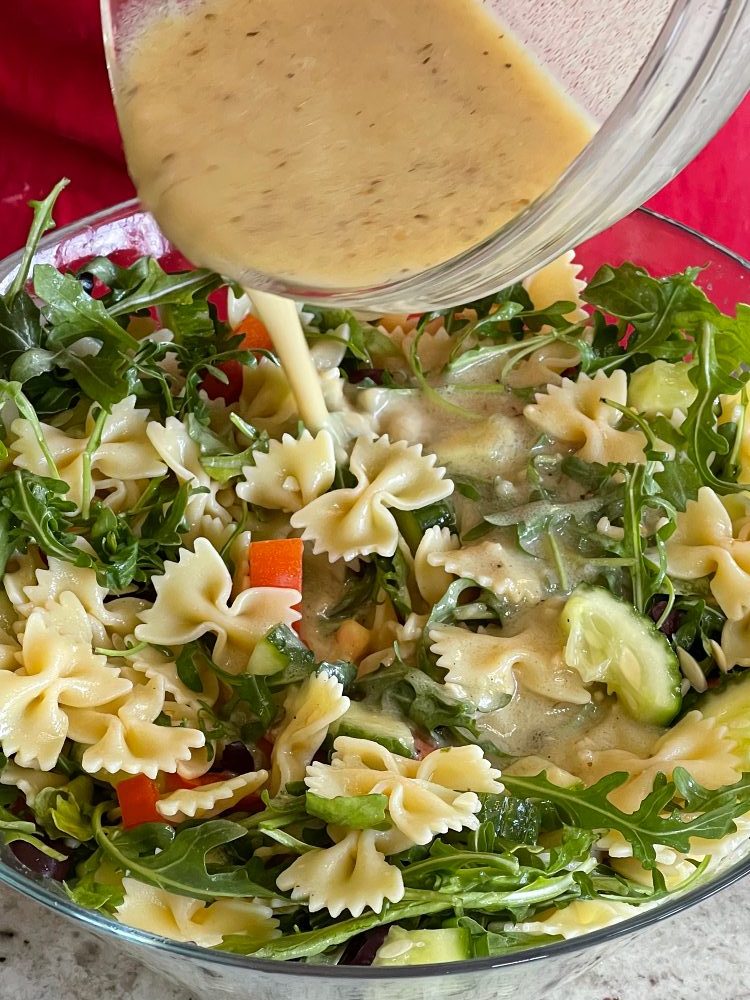 pouring Greek Dressing over Mediterranean salad