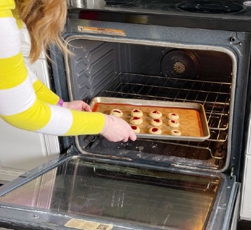putting cookies into oven to bake