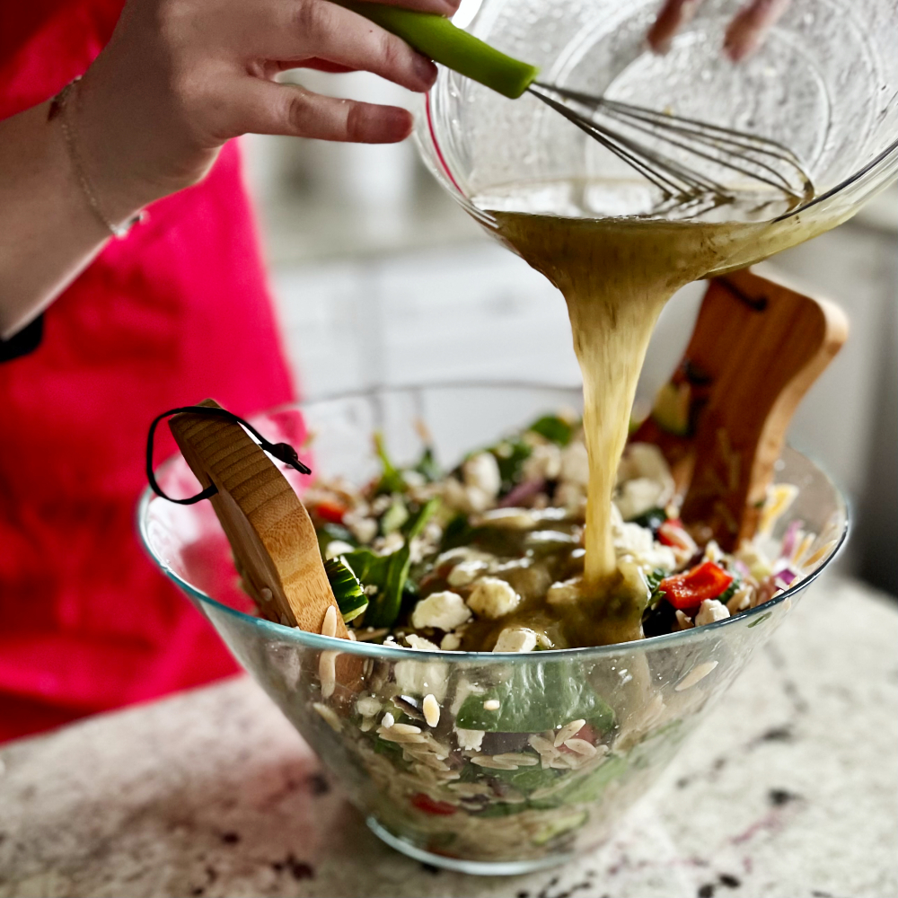 Delicious Greek Orzo Salad with Feta 18 pouring dressing on orzo salad