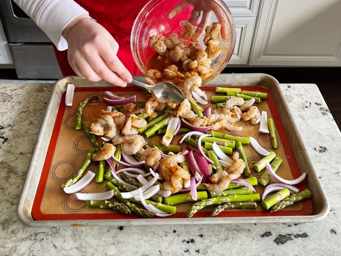 Mediterranean Shrimp Sheet Pan Dinner 18 spooning shrimp over veggies on sheet pan