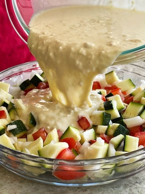 pouring bisquick batter into vegetables-zucchini pie
