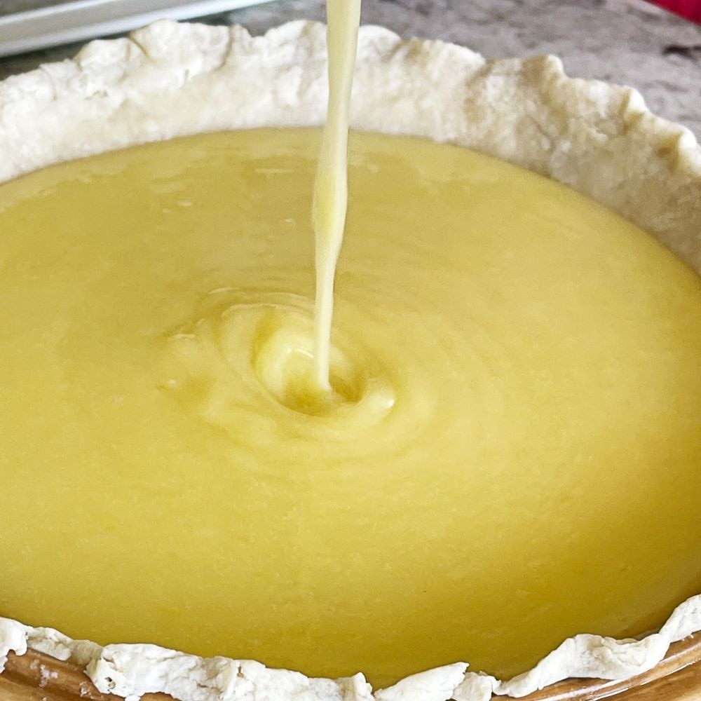 pouring hot lemon curd in baked pie crust