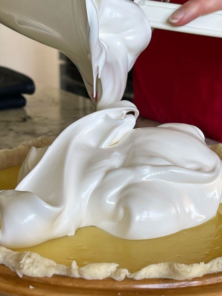 pouring meringue on hot lemon curd