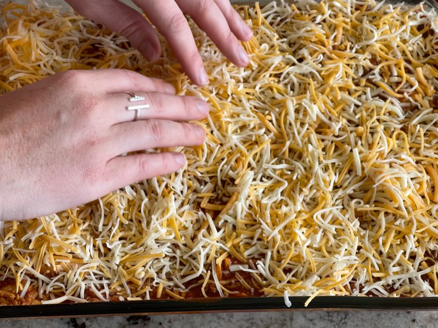 evenly layering cheese as topp layer-chicken enchilada casserole