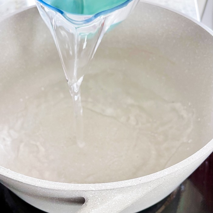 pouring water into large pot on stove