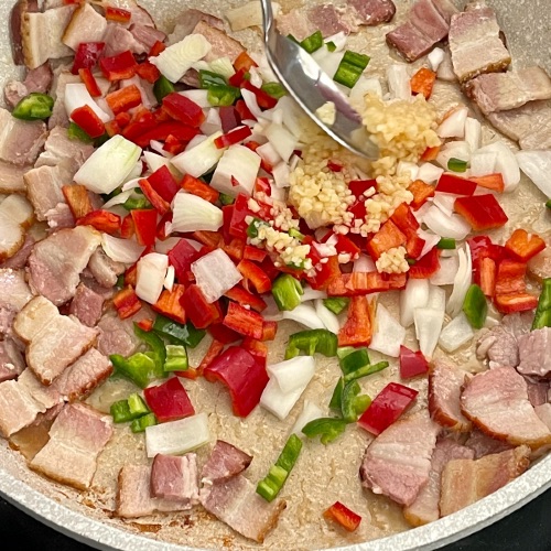 frying bacon, peppers, garlic and onions