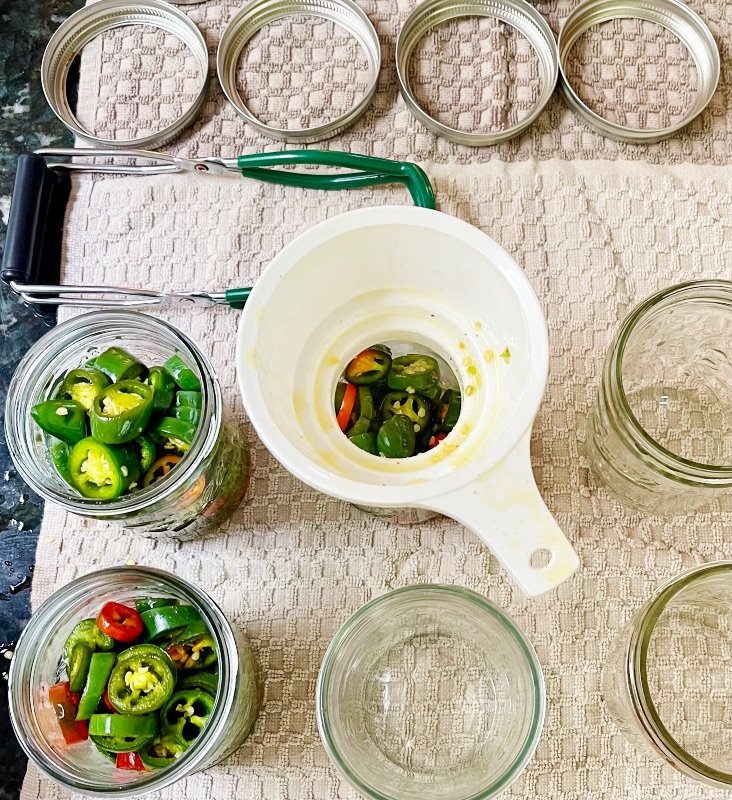filling jars with a canning funnel-candied Jalapenos