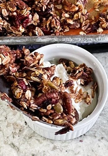 pouring pumpkin granola over yogurt