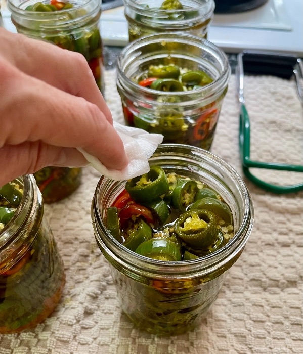wiping the rim of filled canning jars