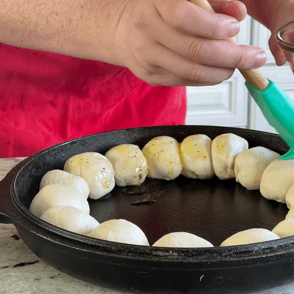 brushing oil and parsley on cresent roll balls