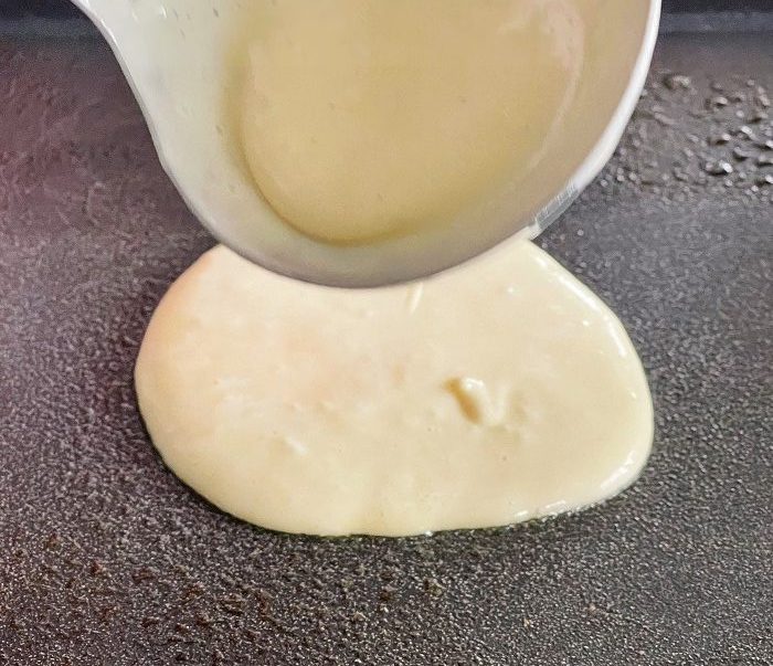 Discard Sourdough Pancakes 8 pouring out sourdough pancake batter on a hot griddle