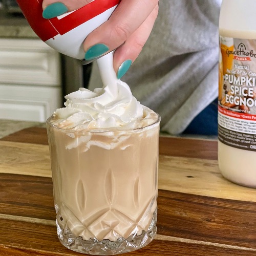 laying whipped cream on eggnog cocktail
