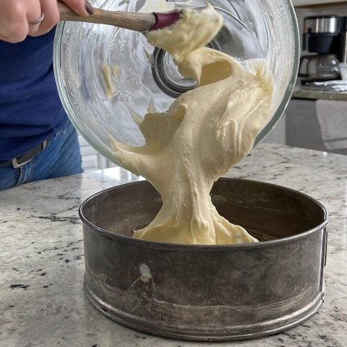pouring cheesecake filling in springform pan.