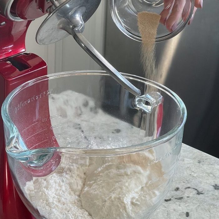 adding yeast to pizza dough mix