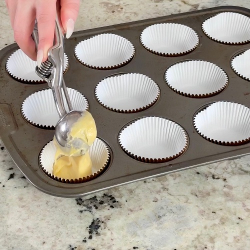 scooping champagne cupcake batter into muffin tin