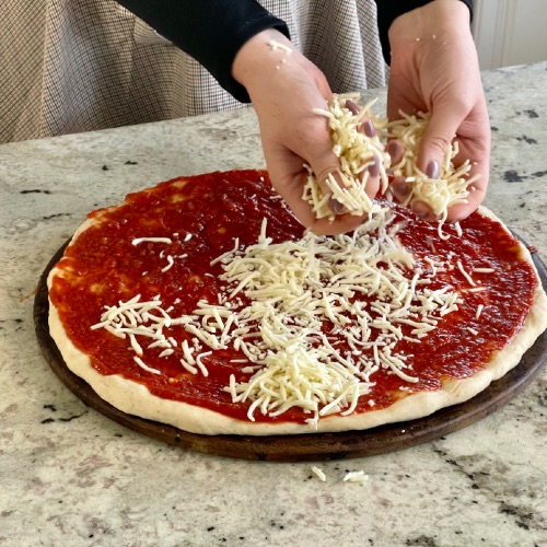 spreading cheese on pizza dough