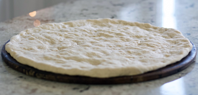 raw sourdough pizza dough formed and ready to bake