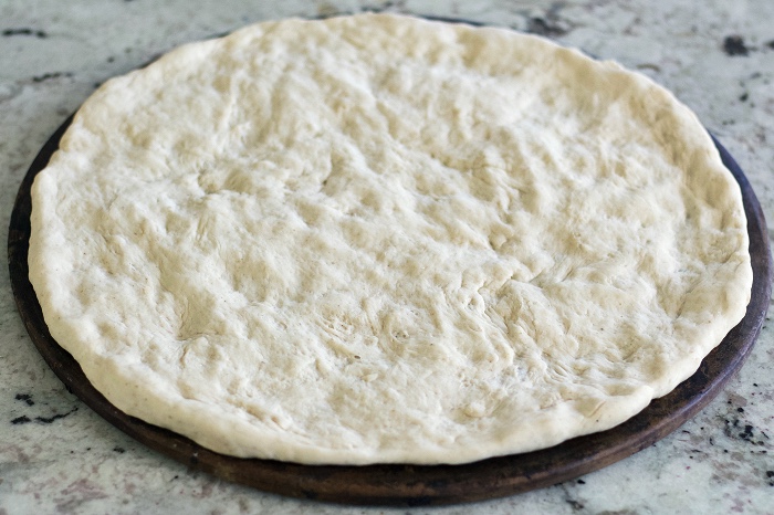 raw pizza dough on pizza stone