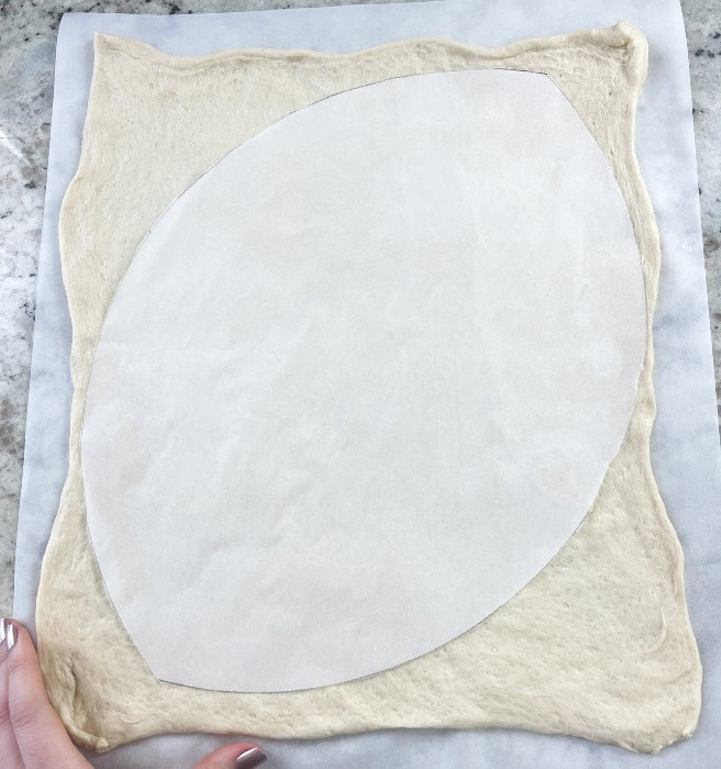 placed parchment cut out on the pizza crust. Ready to shape the pizza.