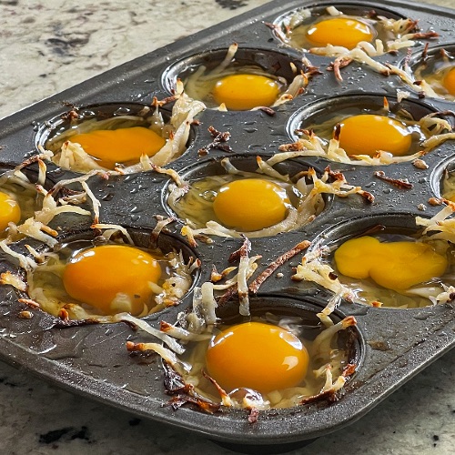 eggs on par baked hash browns in muffin tin. Assembling egg cups