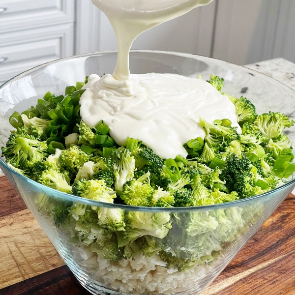 adding dressing to broccoli cauliflower salad