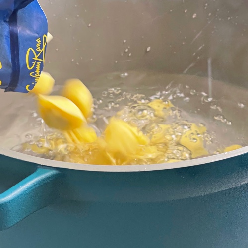 pouring tortellini into boiling water