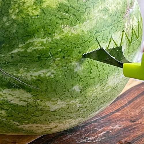 cutting a saw toothed edge on a watermelon