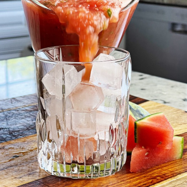 pouring watermelon jalapeno pulp into glass with ice